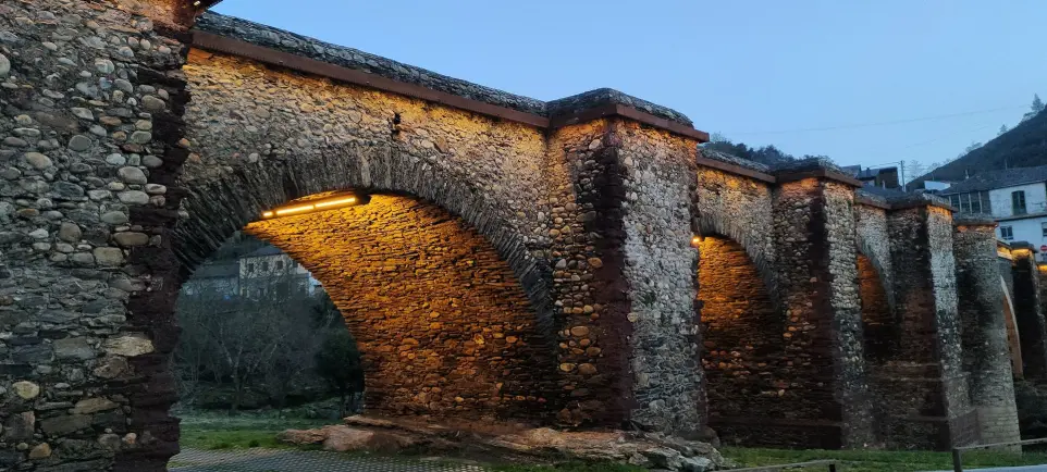 Proyecto de iluminación Luxes en el Puente de Sobradelo: luz LED cálida que realza la arquitectura histórica al anochecer. Iluminación LED cálida en los arcos del Puente de Sobradelo, resaltando su estructura de piedra con diseño de Luxes.