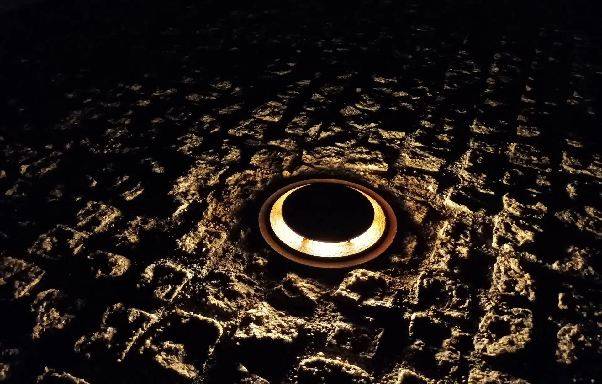 Proyecto de iluminación Luxes en el Puente de Sobradelo: luminarias LED empotradas que destacan texturas y patrimonio histórico. Detalle de luminaria LED empotrada en piedra del Puente de Sobradelo, proyecto lumínico de Luxes.