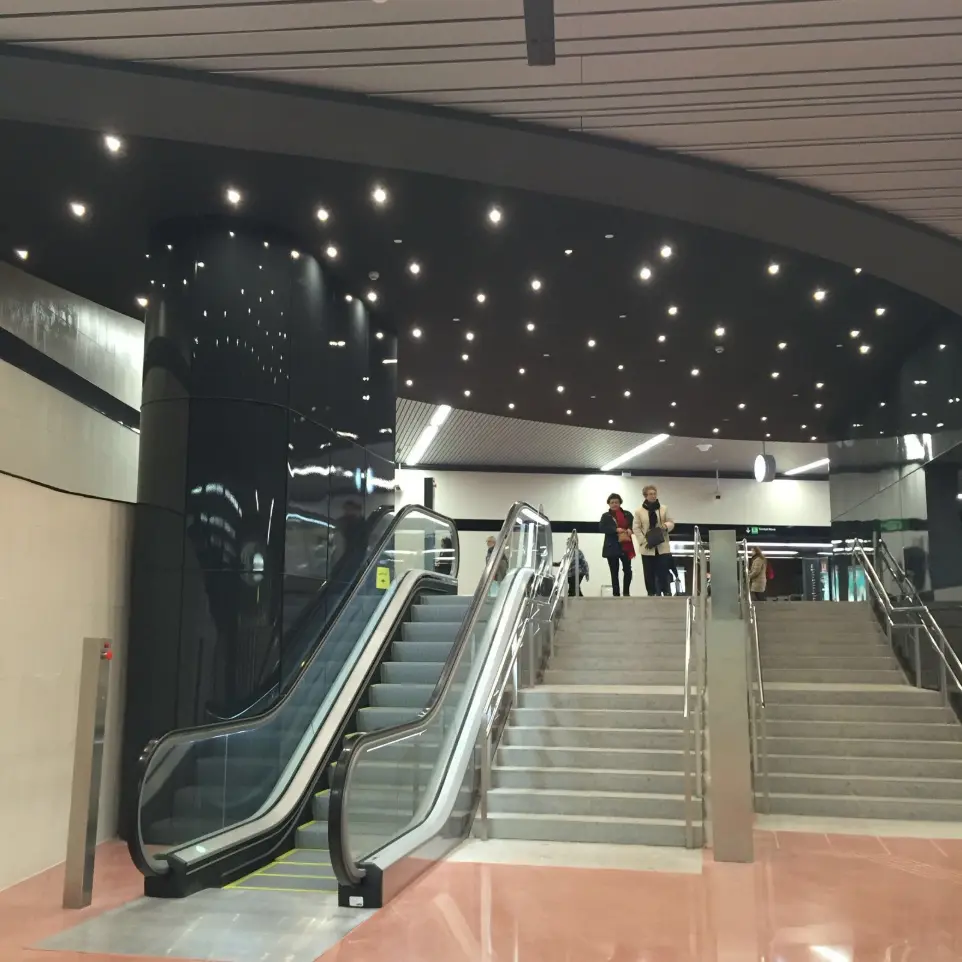 Escaleras mecánicas y acceso principal iluminado con downlights LED en Plaça Universitat.