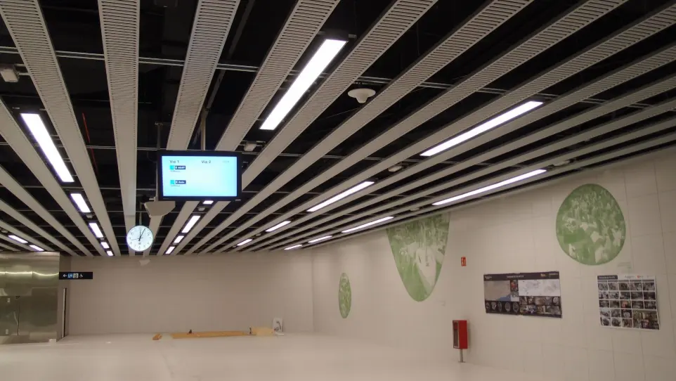 Iluminación técnica con luminarias lineales y señalización digital en el vestíbulo de la estación de metro Foc.