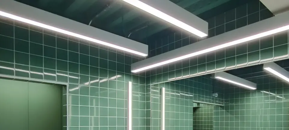 Iluminación LED arquitectónica de LUXES en espacios con azulejos verdes de Lasenor, diseño contemporáneo y funcional.
