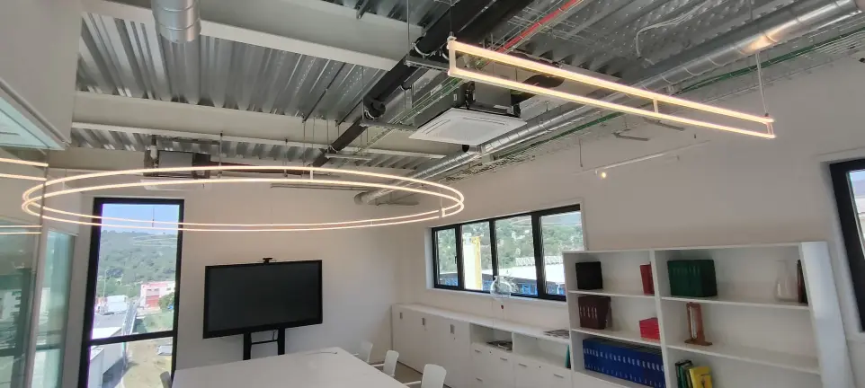 Luminarias LED circulares y lineales instaladas por LUXES en las oficinas de Lasenor, combinando luz natural y eficiencia energética.