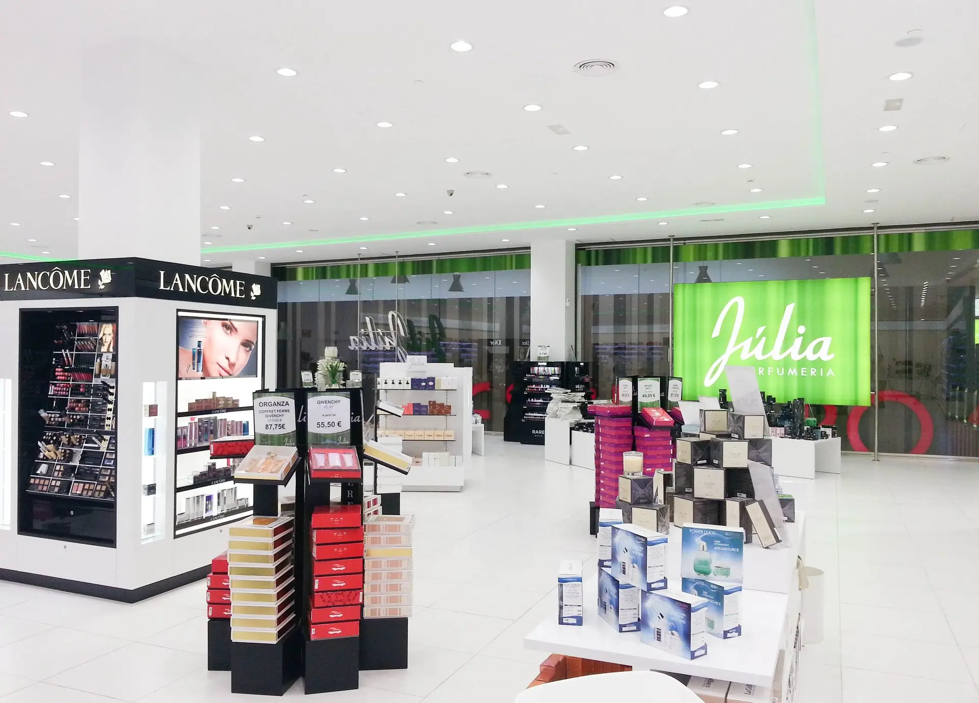 Iluminación técnica y decorativa en Perfumería Júlia con acentos verdes y luz LED uniforme.