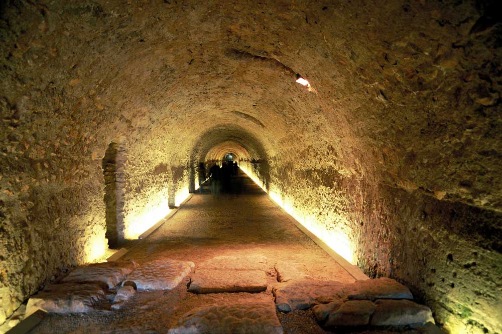 Iluminación LED arquitectónica en el pasadizo del Circo Romano de Tarragona, resaltando la piedra histórica con diseño de Luxes.